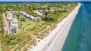 Oversigtsbillede af et kystresort med ejendomme ved stranden, en golfbane og frit udsyn til havet.