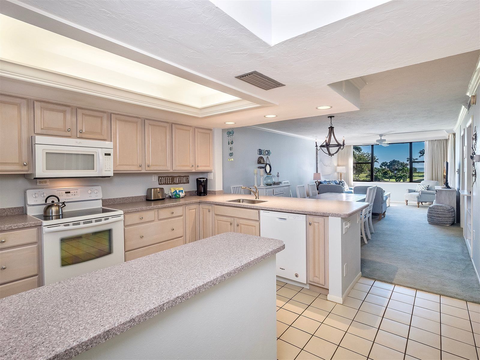 Een moderne keuken met een centraal eiland, inbouwapparatuur en uitzicht op de woonkamer.