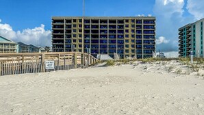 Un hôtel à plusieurs étages avec vue sur la plage, un drapeau au sommet et une enseigne indiquant le nom de la plage.