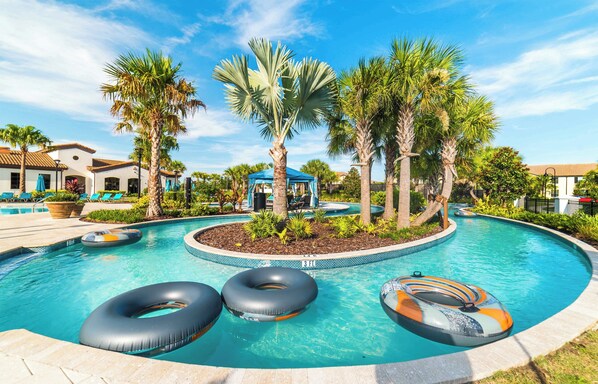 A swimming pool with palm trees, lounge chairs, and a blue gazebo.