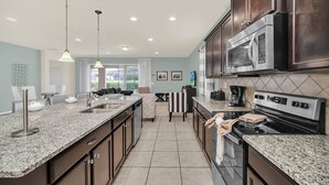 Una cocina moderna con encimeras de granito, electrodomésticos de acero inoxidable y armarios de madera oscura.