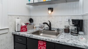 A kitchen with a granite countertop, stainless steel sink, and a coffee maker. - Zen Den at Rockaway Rentals near Branson (Rockaway Beach)