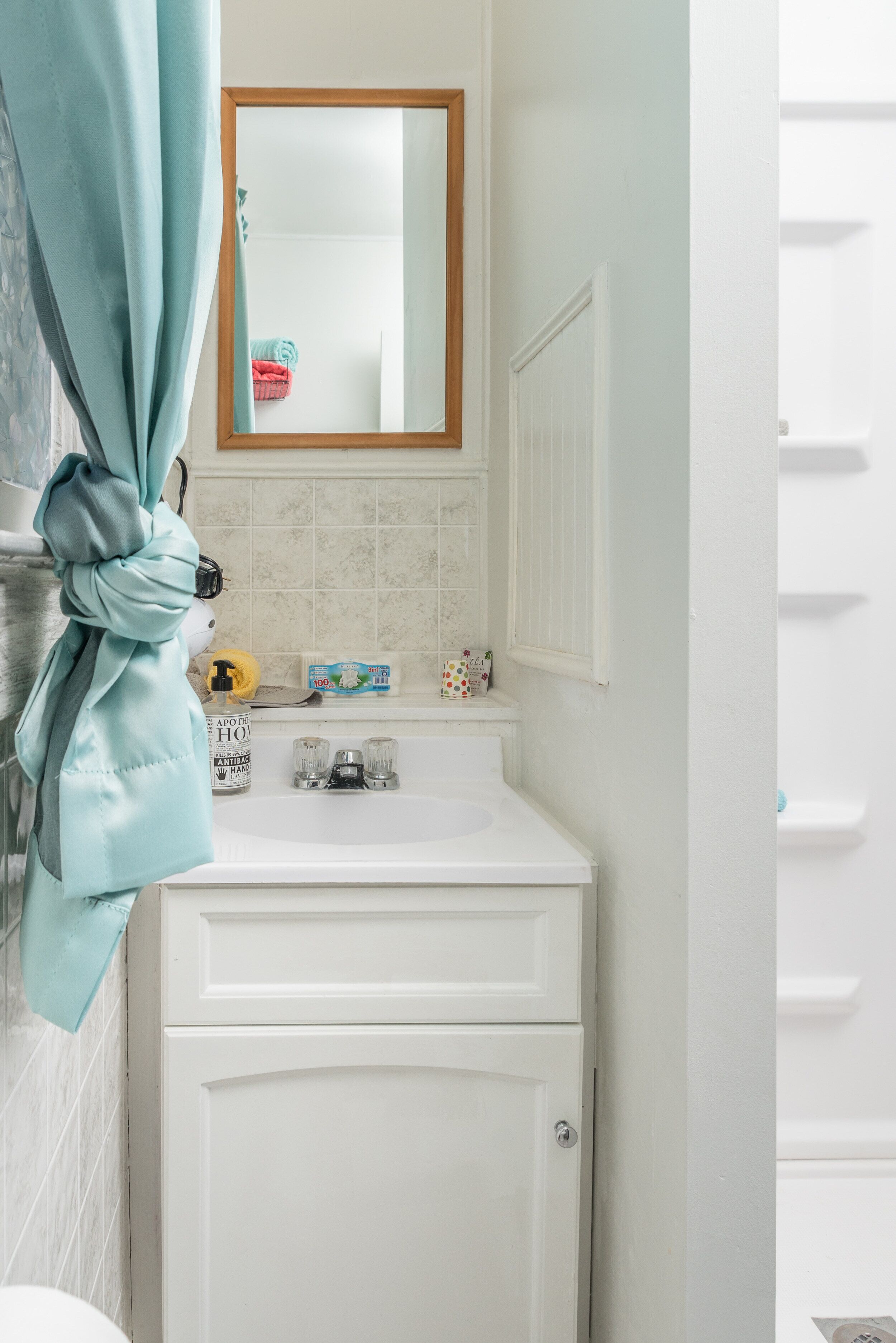 A bathroom with a white sink, a mirror, and a towel rack.