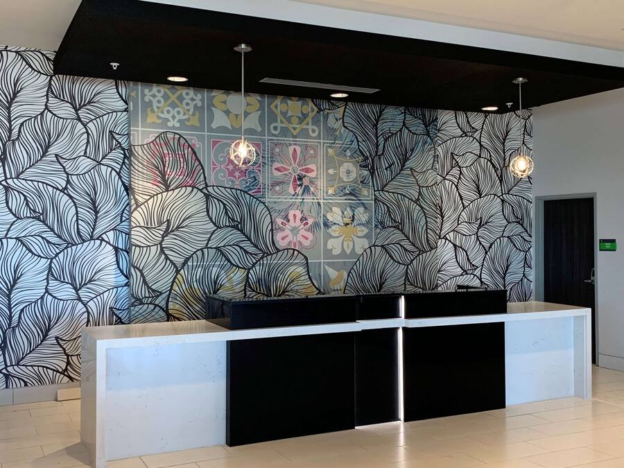 A reception area with a modern design, featuring a patterned wall and a black reception desk.