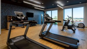 Une salle de sport équipée de tapis de course, d’un vélo elliptique et d’un rameur.