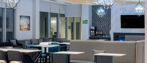 Een modern restaurant met zitplaatsen, tafels en hangende kroonluchters.