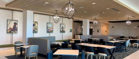 A modern restaurant with wooden ceiling, pendant lighting, and artwork on the walls.