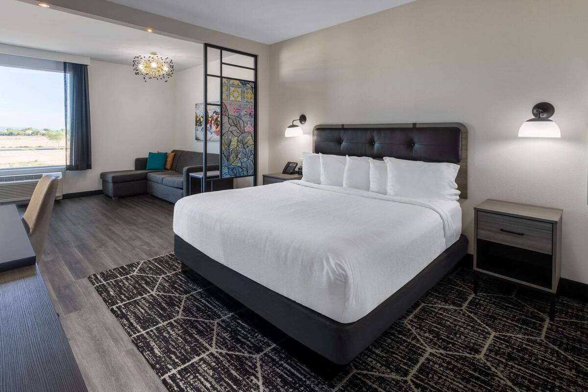 Une chambre d’hôtel moderne dotée d’un grand lit, d’un bureau, d’une chaise, d’un canapé et offrant une vue sur l’extérieur.