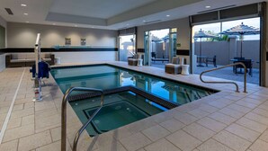 Une piscine avec un plongeoir, des chaises longues et un espace extérieur aménagé avec des parasols.