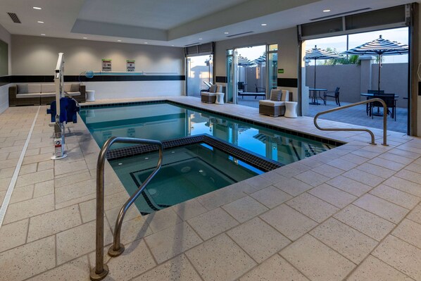 A swimming pool with a diving board, lounge chairs, and a patio area with umbrellas.