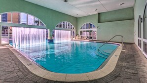 An indoor swimming pool with clear water, a tiled floor, and arched windows. - Waterfront High-Rise PCB Condo w/ Community Perks (Panama City Beach)