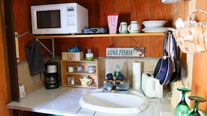 A compact kitchen with a microwave, coffee maker, and a 'Gone Fishin'' sign.