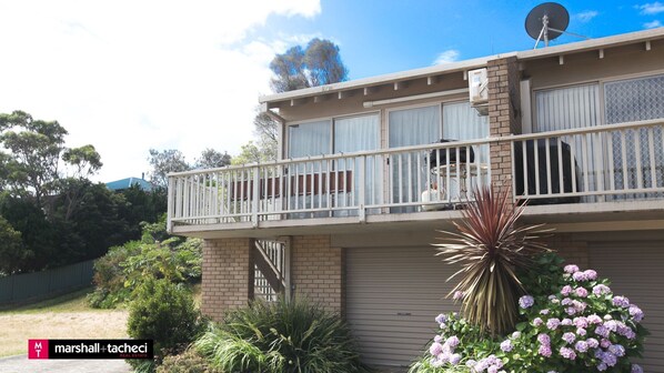 A two-story building with a balcony, brick walls, and a satellite dish. - Outlook 1 - Unit 1 Narira St 9 (BERMAGUI)