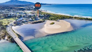 An aerial view of a coastal area with a bridge, clear waters, and a sign for South Coast Accommodation.