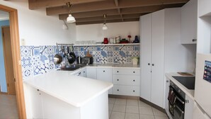 A kitchen with white cabinets, a tiled backsplash, hanging pots, and a microwave. - Outlook 1 - Unit 1 Narira St 9 (BERMAGUI)