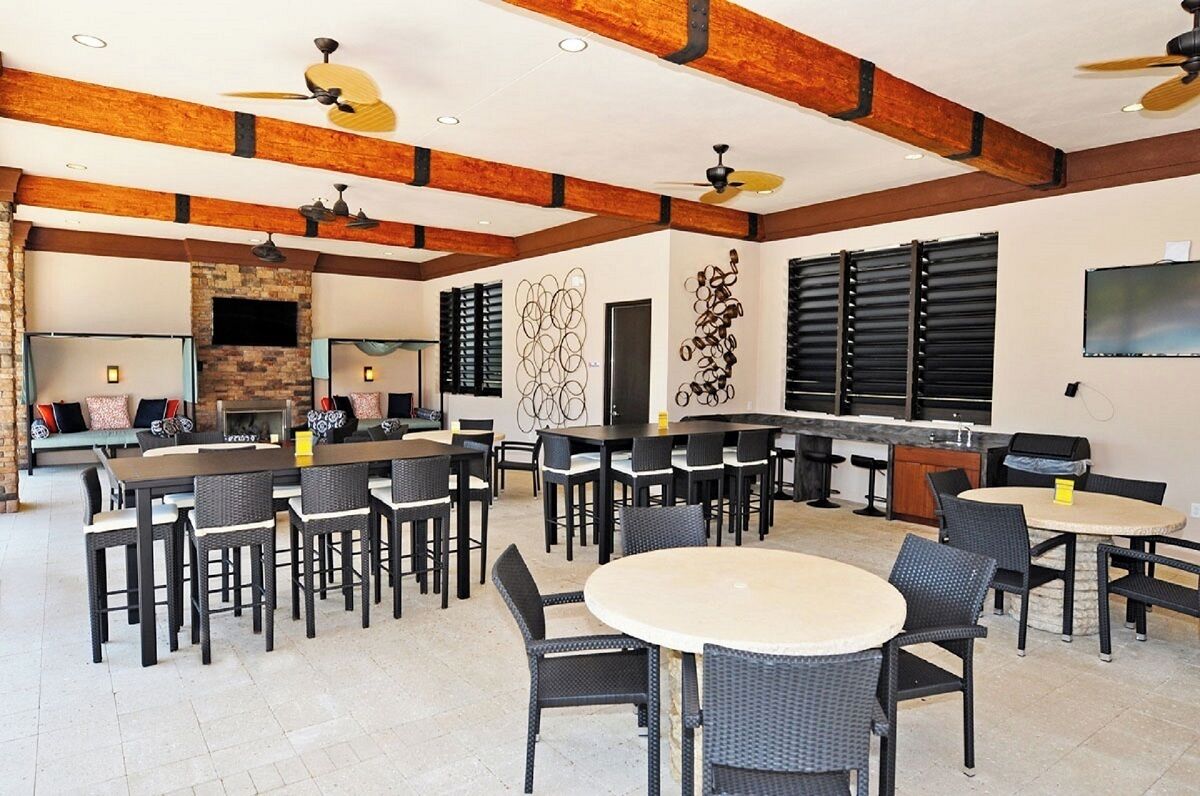 A spacious indoor dining area with multiple tables and chairs, a kitchen area with a grill, and a seating area with a bench.