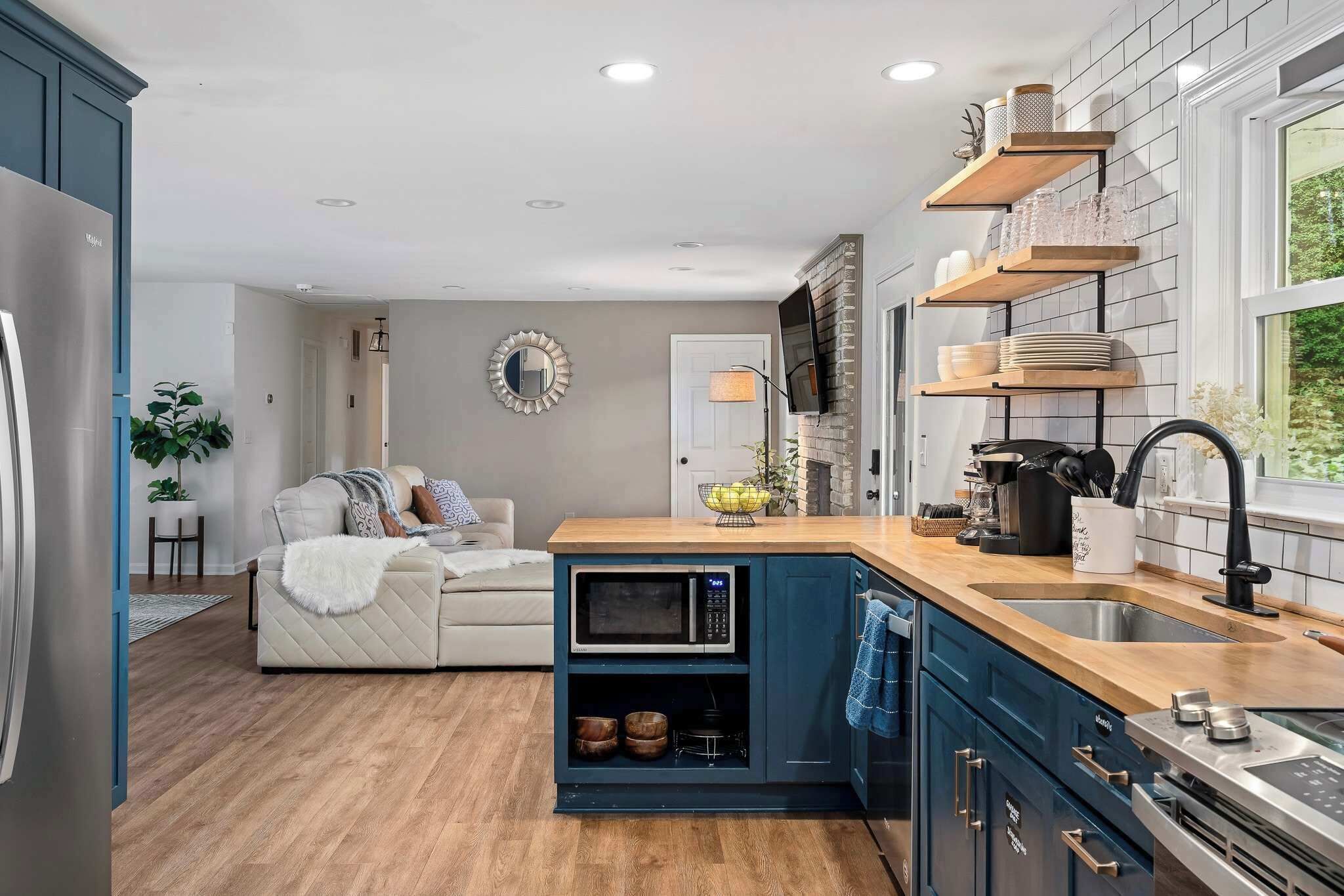 A compact kitchen with built-in appliances, a wooden countertop, and a view of the outdoors.