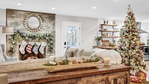 A cozy living room with a fireplace, a Christmas tree, and a rustic wooden coffee table. - The Gathering Grove (Tucker)