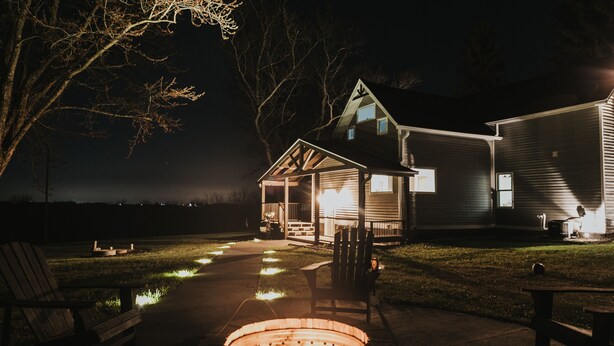 A house with a fire pit, outdoor seating, and a well-lit porch.