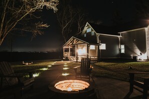 A house with a fire pit, outdoor seating, and a well-lit porch. - Private 30 Acre Farm W/ Walking Trails - Sleeps 10, Unwind & Enjoy the outdoors. (Houston)