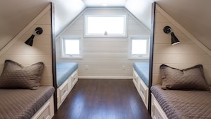 A small attic bedroom with two beds, a skylight, and a window.