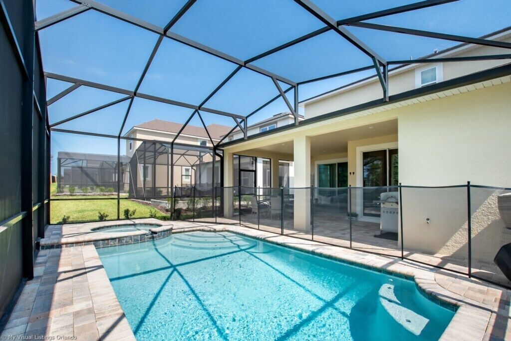 Ein Schwimmbecken mit Glasabdeckung, umgeben von einer Terrasse mit einer Umzäunung.