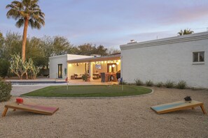 A backyard with a pool, a wooden deck, and a patio area with outdoor furniture. - Olive Tree Retreat | Heated Pool, Patio & Privacy (Scottsdale)