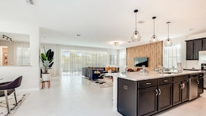 A modern kitchen with a large island, dark cabinetry, and pendant lighting. - New Listing! Solara Resort, 8mi to Disney & 15mi to Universal - FS317744 (Kissimmee)