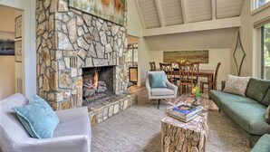 Una sala de estar acogedora con chimenea de piedra, asientos cómodos y un comedor con mesa y sillas.