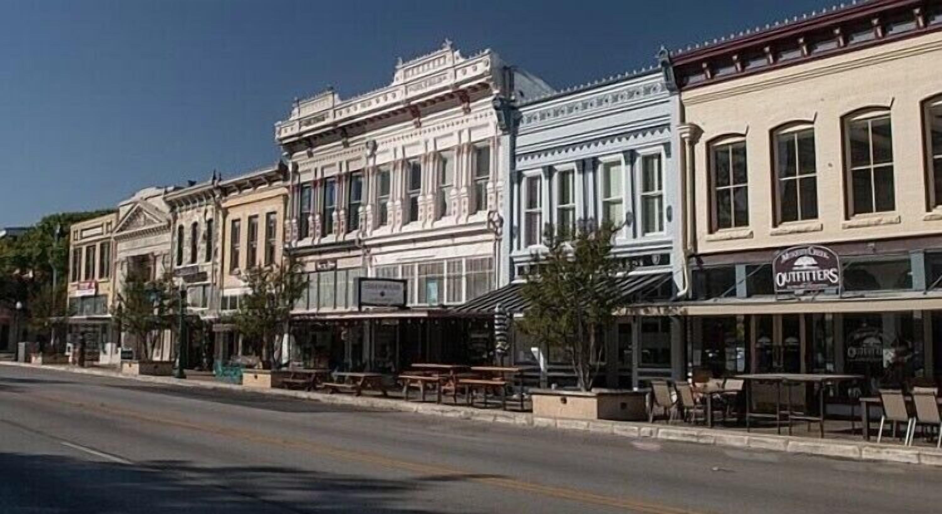 A row of historic buildings with storefronts, including a visible sign for 'Outfitters'.