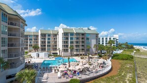 A hotel with multiple floors, a swimming pool, and a beach view.