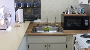 A compact kitchen with a sink, microwave, stove, and a fan. - San Juan Sunrise - Apex Living in the Capital of Puerto Rico (San Juan)