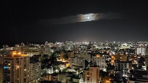 A nighttime cityscape with illuminated buildings and a visible moon. - San Juan Sunrise - Apex Living in the Capital of Puerto Rico (San Juan)