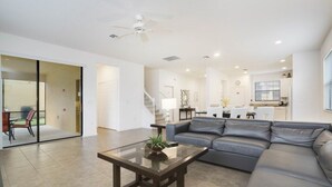 A modern living room with a glass coffee table, grey leather sofa, and a dining area in the background. - New Listing! Providence Resort, 9mi to Disney & 18mi to Universal - FS326676 (Davenport)