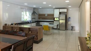A modern kitchen with a central island, a dining area with a wooden table, and a kitchen counter with a sink and stove. - Incredible country house in Salesopolis (Salesópolis)