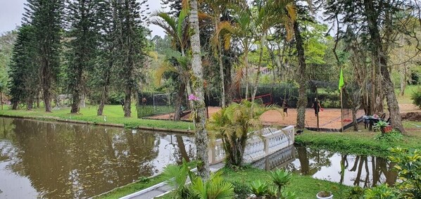 Um parque tranquilo com um lago, vegetação exuberante e um coreto.