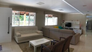 A spacious living room with a sofa, a coffee table, and a TV. - Incredible country house in Salesopolis (Salesópolis)