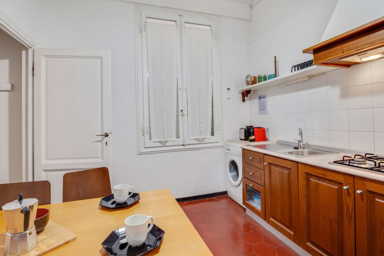 Une cuisine compacte équipée d’un lave-linge, d’un évier et d’un coin repas avec une table et des chaises.