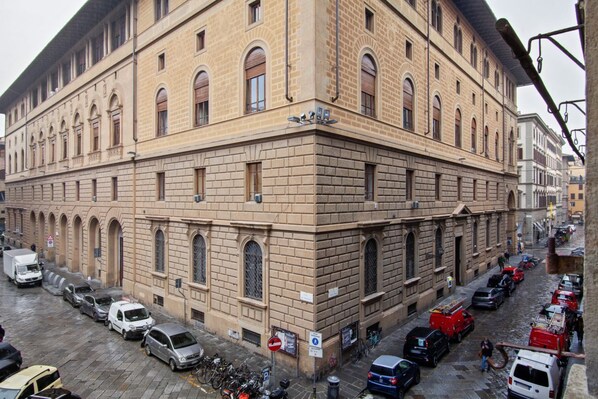 Un edificio grande e histórico con una fachada simétrica, múltiples ventanas y una entrada en esquina.