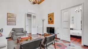 Una sala de estar con un sofá, sillas, un televisor y un cuadro en la pared.