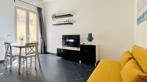 Moderni olohuone, jossa on ruokailutila, televisio ja sohva.