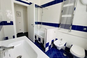 Tina con regadera, secadora de cabello, bidet, toallas 