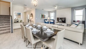 Un salon moderne comprenant un coin repas, un escalier et une cuisine.