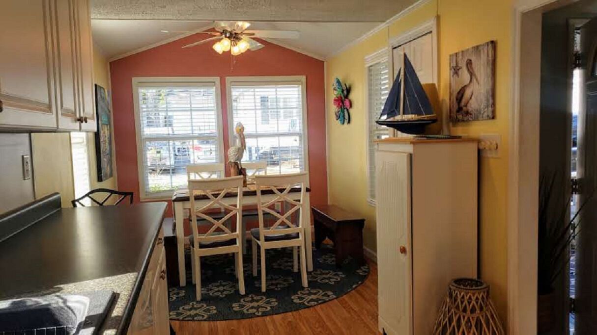 A kitchen with a dining area, a refrigerator, and a window with blinds.