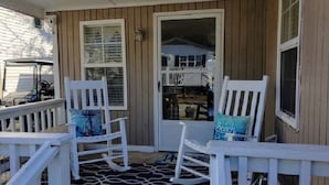 A porch with white rocking chairs and a door leading to a garage. - Ocean Lakes Pelican Pointe, Beautiful Ocean & Lake Front cozy cottage. (Myrtle Beach)