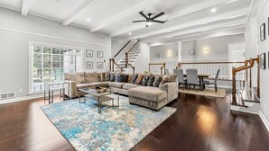 A spacious living room with a large sectional sofa, a coffee table, and a staircase with wooden railings.