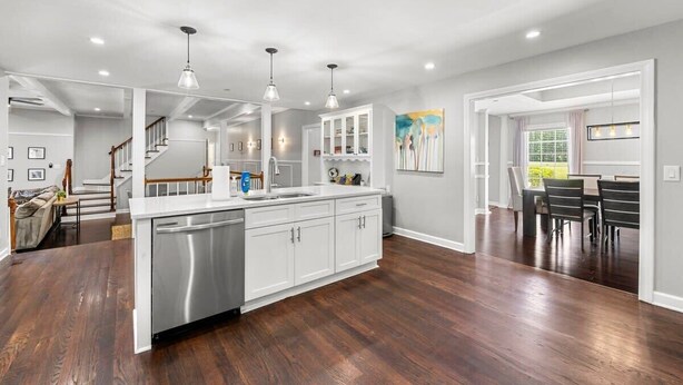A modern kitchen with white cabinets, stainless steel appliances, and pendant lighting.