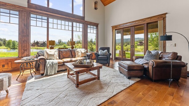 Amplia sala de estar con ventanas grandes, una chimenea y vistas a un lago.