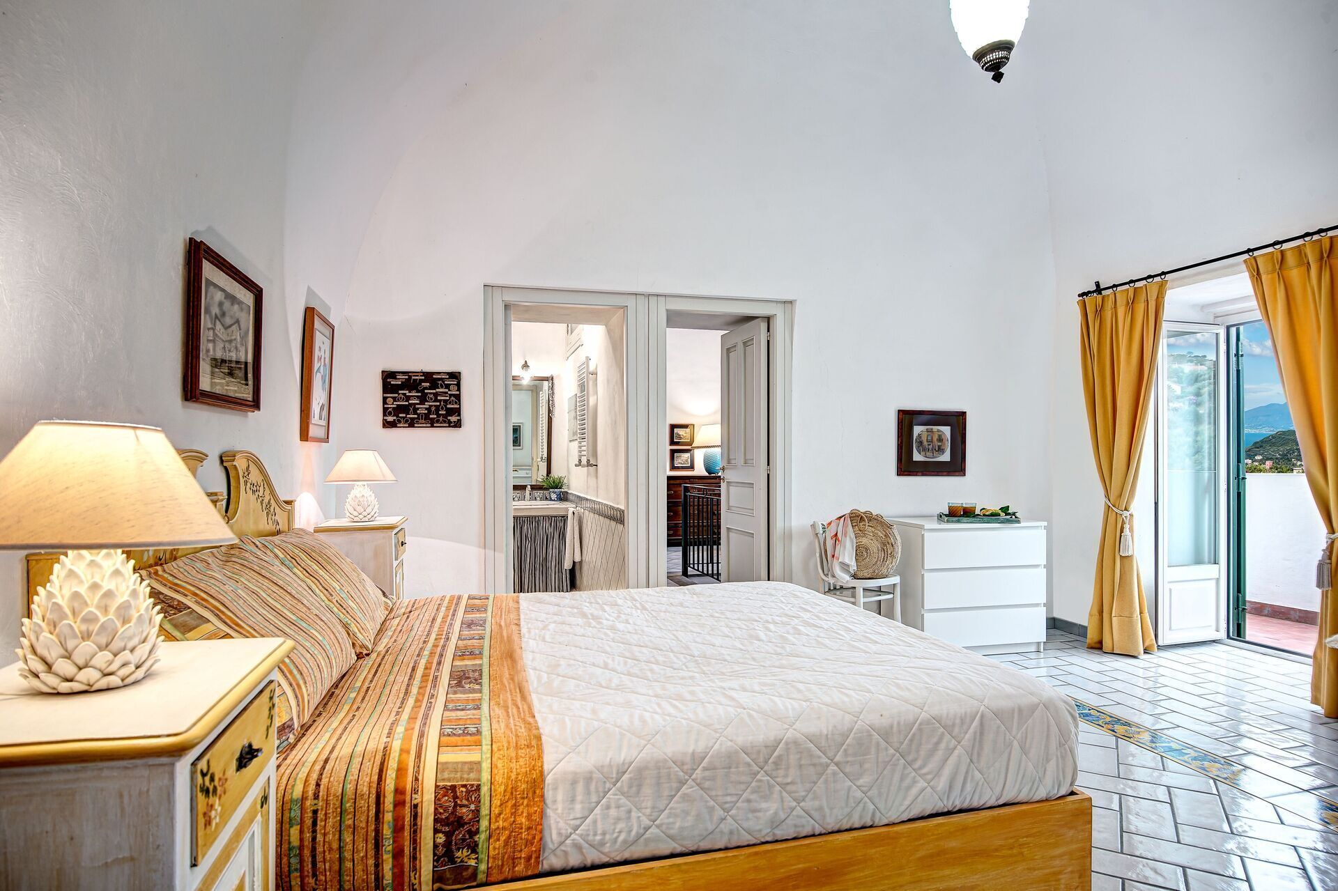 Ein Schlafzimmer mit Bett, Nachttischen, einem Spiegel und Blick ins Freie.