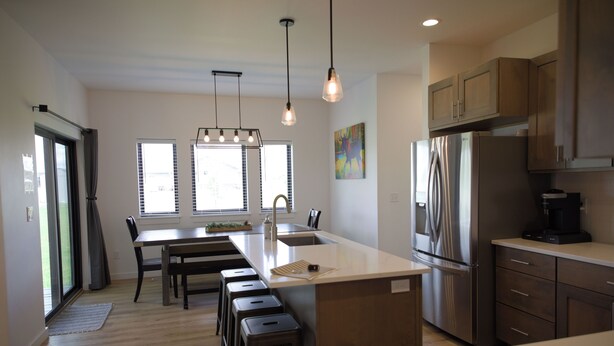 A modern kitchen with a central island, stainless steel appliances, and pendant lighting.